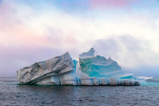 Iceberg on Disko Bay Greenland with rising sea mist behind it.