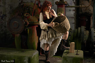 Female model in costume standing with basket in old pumping station. 