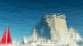 water reflection of red sails of boat and iceberg