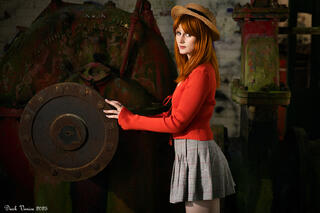 Female model in school skirt and red top and hat in old pumping station.