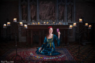 Female model in medieval dress with tarot cards in front of an altar in an old church. 